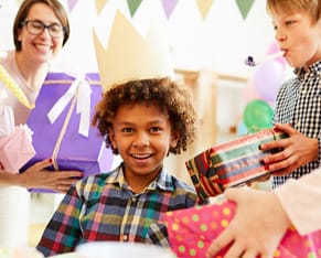 Criança comemorando com chapéu de festa, presente de aniversário.
